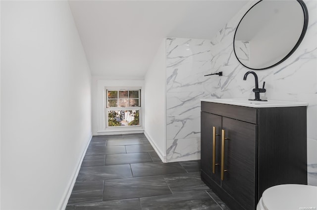 bathroom with vanity, toilet, and tile walls