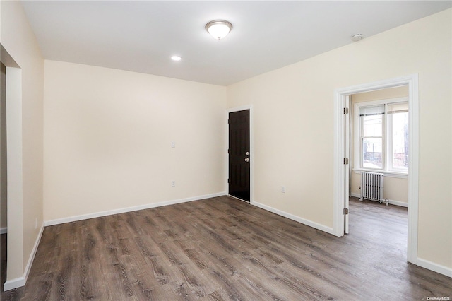 empty room featuring radiator heating unit and dark wood-type flooring