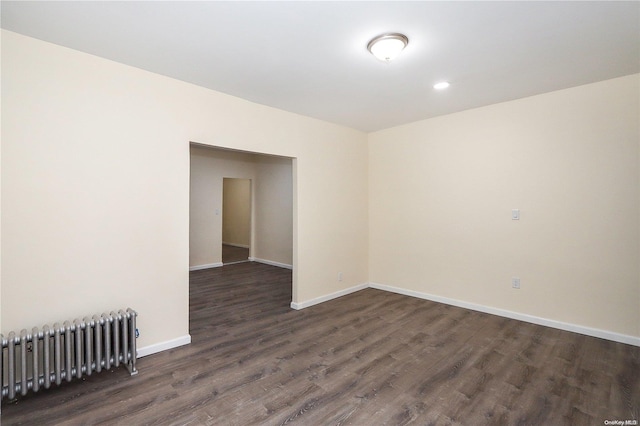 spare room featuring radiator heating unit and dark wood-type flooring