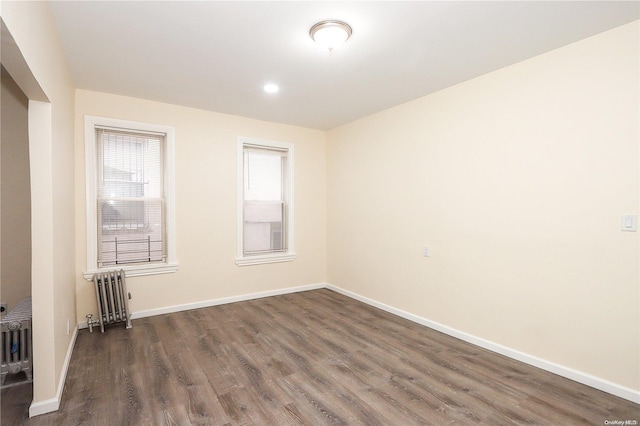 spare room with dark hardwood / wood-style floors and radiator heating unit