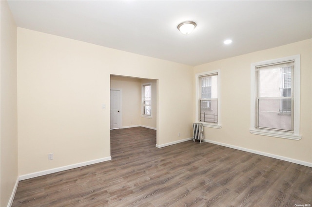 spare room with radiator heating unit and dark hardwood / wood-style floors