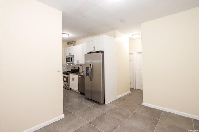 kitchen with tile patterned floors, stainless steel appliances, white cabinetry, and tasteful backsplash