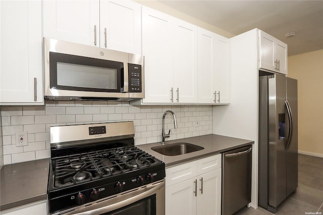 kitchen with white cabinetry, sink, dark tile patterned floors, decorative backsplash, and appliances with stainless steel finishes