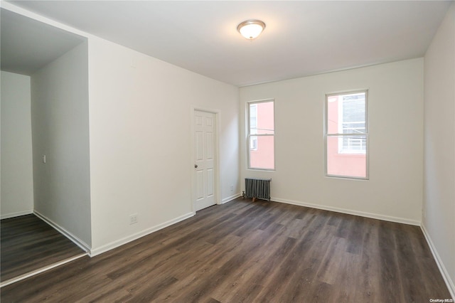 spare room with radiator heating unit and dark hardwood / wood-style floors