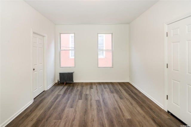 empty room featuring radiator heating unit and dark hardwood / wood-style flooring