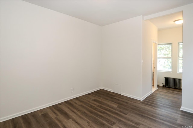 spare room featuring dark hardwood / wood-style floors and radiator