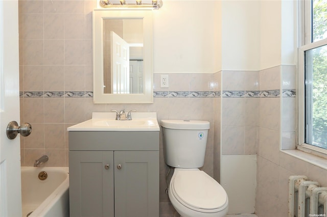 bathroom with vanity, a washtub, tile walls, and radiator