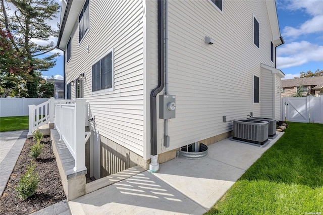 view of side of home featuring a patio area, central air condition unit, and a yard