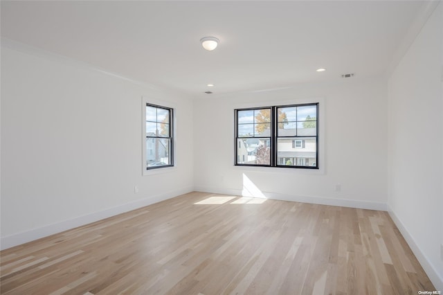 unfurnished room featuring light wood-type flooring, a wealth of natural light, and ornamental molding