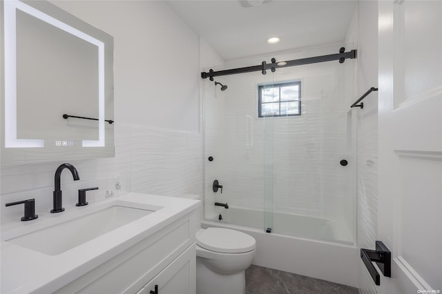 full bathroom featuring vanity, shower / bath combination with glass door, tile patterned floors, toilet, and tile walls