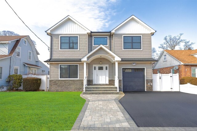 view of front facade with aphalt driveway, a gate, fence, stone siding, and a front lawn