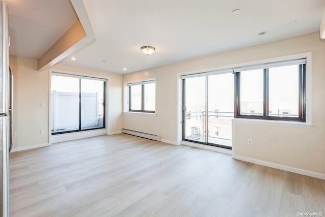 empty room with light hardwood / wood-style floors and baseboard heating