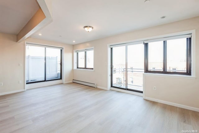 empty room with a baseboard radiator, plenty of natural light, and light hardwood / wood-style floors