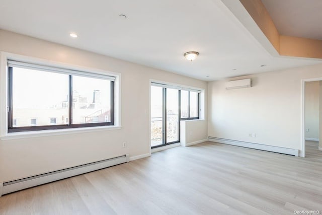 empty room featuring a wall mounted air conditioner, light hardwood / wood-style floors, and baseboard heating