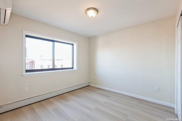 unfurnished room featuring light hardwood / wood-style flooring and a baseboard heating unit