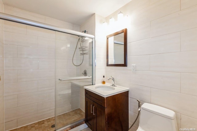 bathroom with vanity, toilet, tile walls, and a shower with shower door