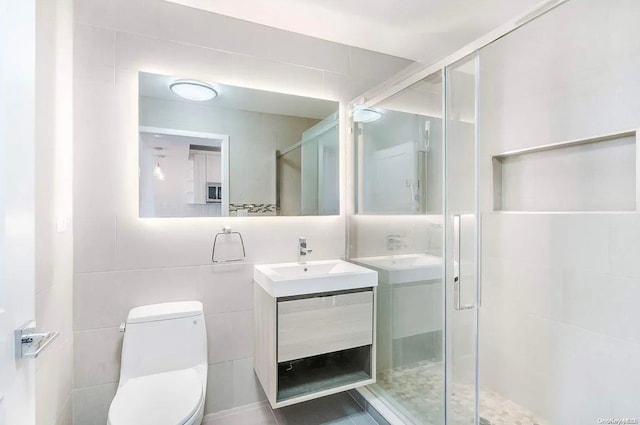 bathroom featuring walk in shower, vanity, tile walls, and toilet