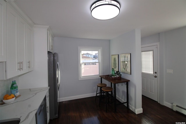 kitchen with a baseboard radiator, light stone counters, dark hardwood / wood-style floors, stainless steel fridge, and white cabinets