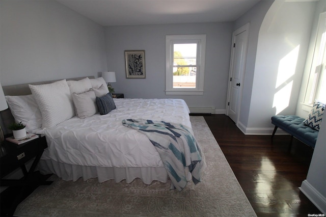 bedroom with dark hardwood / wood-style floors and a baseboard radiator