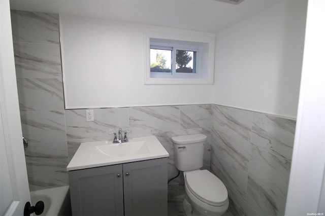 bathroom featuring vanity, tile walls, and toilet