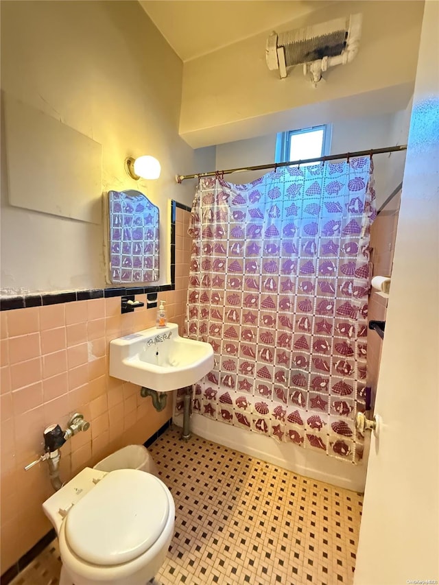 full bathroom featuring tile patterned floors, toilet, shower / bathtub combination with curtain, and tile walls