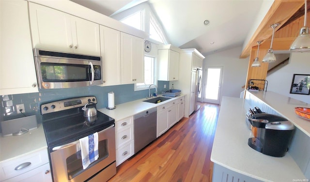 kitchen with sink, hanging light fixtures, stainless steel appliances, lofted ceiling, and white cabinets