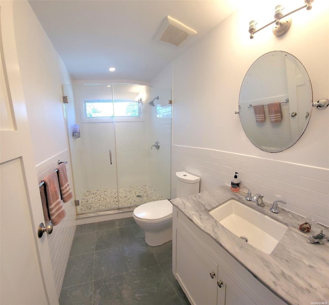 bathroom with tile patterned floors, walk in shower, vanity, tile walls, and toilet