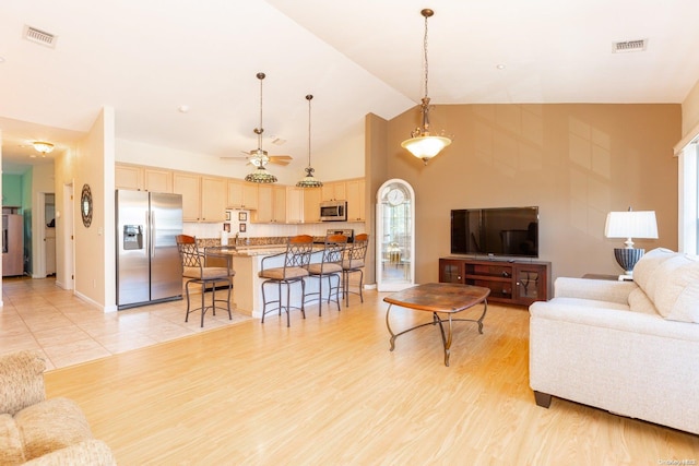 living room with ceiling fan, light hardwood / wood-style flooring, and high vaulted ceiling