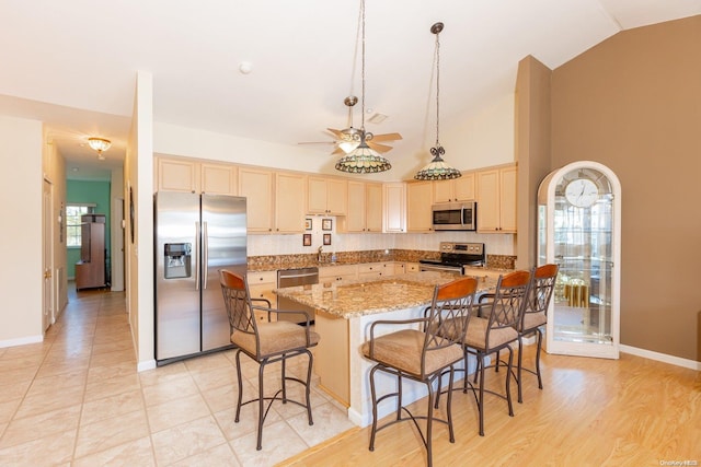 kitchen featuring vaulted ceiling, stainless steel appliances, a kitchen island, and plenty of natural light