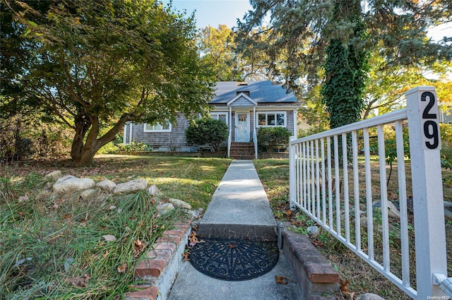 view of front of home with a front yard and solar panels