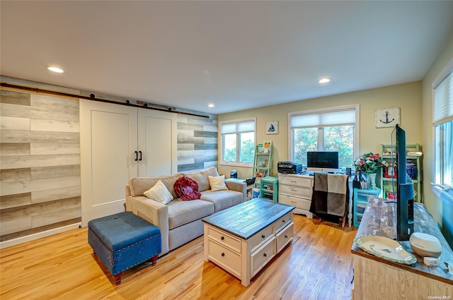 living room featuring a barn door, wooden walls, and light hardwood / wood-style flooring