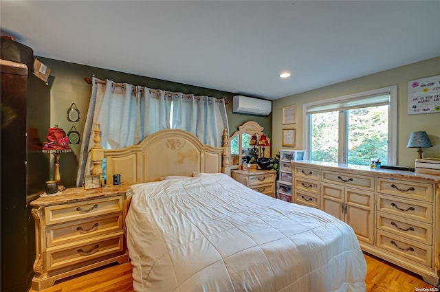 bedroom with light hardwood / wood-style flooring and an AC wall unit