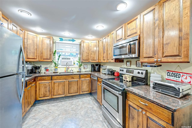 kitchen with dark stone counters, sink, light tile patterned floors, and stainless steel appliances