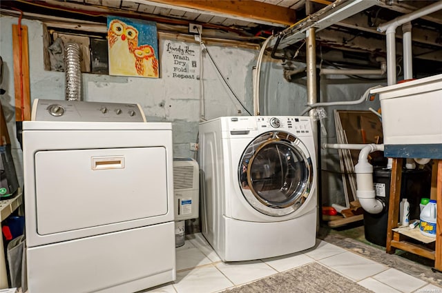 clothes washing area featuring light tile patterned floors and washing machine and clothes dryer