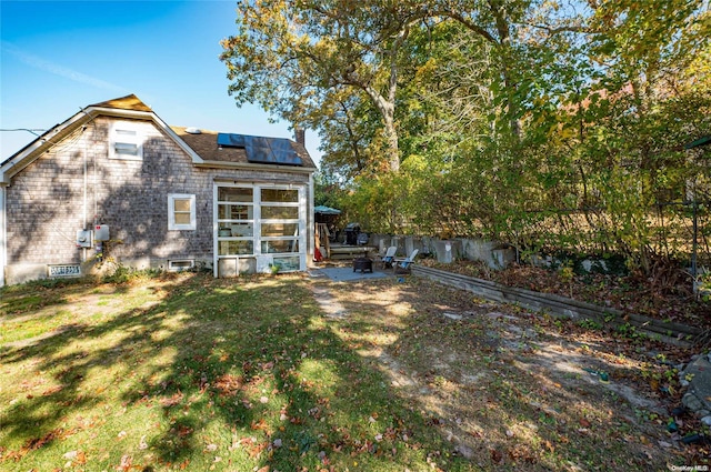 back of property with a lawn, solar panels, and a patio area