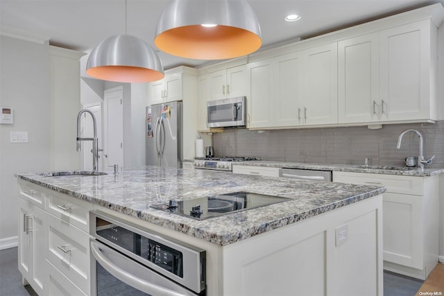 kitchen with a kitchen island with sink, sink, appliances with stainless steel finishes, tasteful backsplash, and white cabinetry