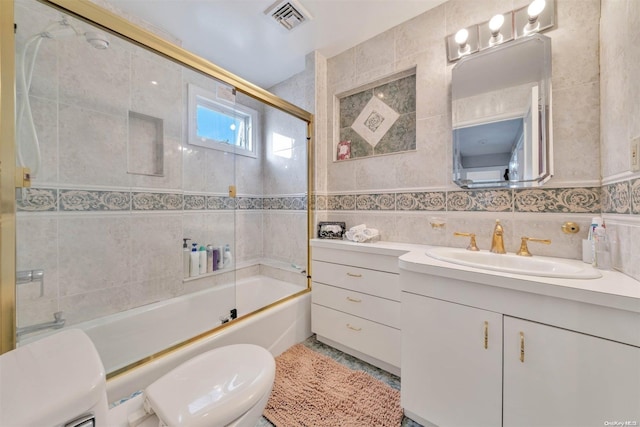 full bathroom with vanity, toilet, tile walls, and enclosed tub / shower combo