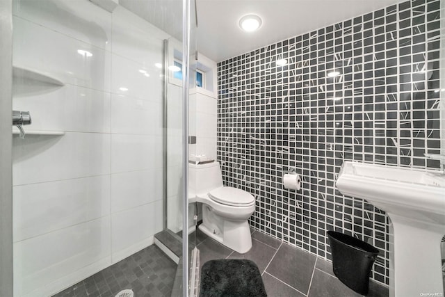 bathroom with tile patterned floors, a shower, tile walls, and toilet