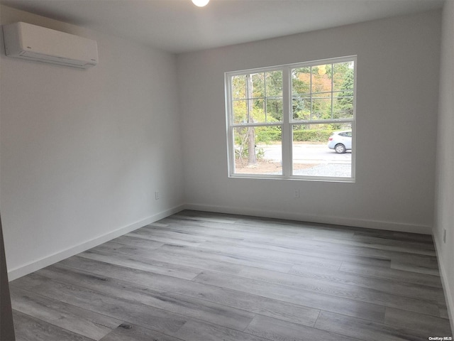 empty room featuring light hardwood / wood-style floors and a wall mounted AC