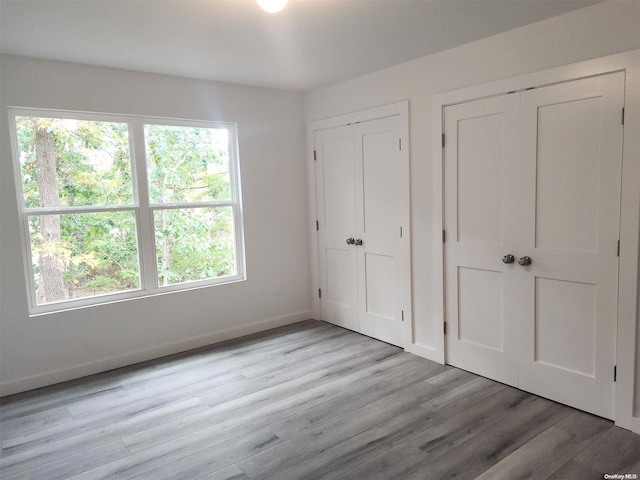 unfurnished bedroom featuring multiple closets and light wood-type flooring