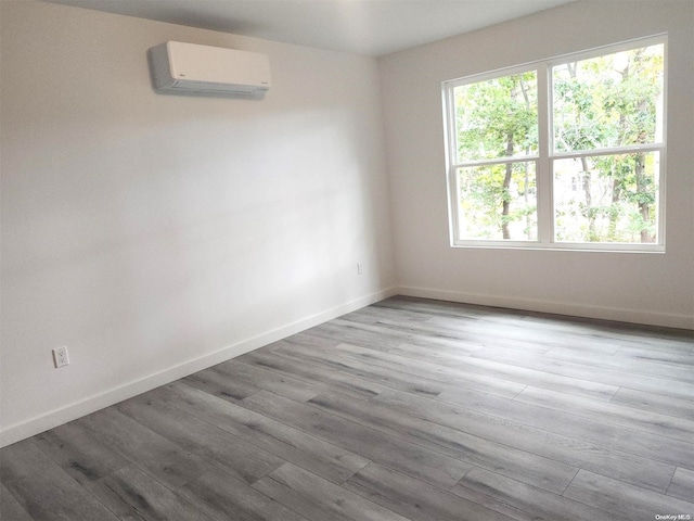 spare room with light wood-type flooring and a wall unit AC