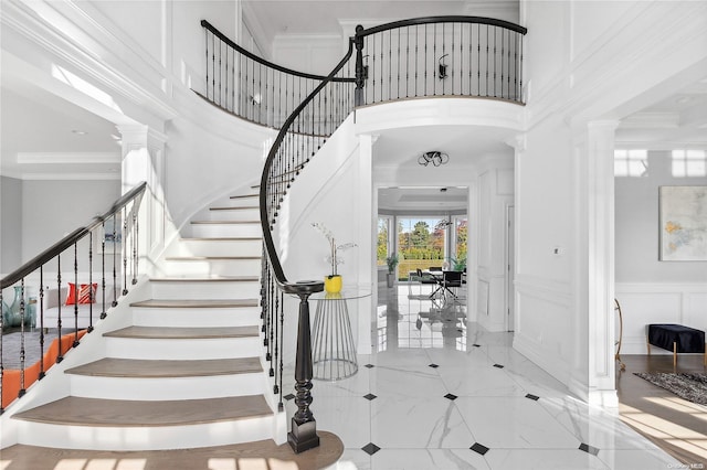 foyer with decorative columns, a towering ceiling, and ornamental molding