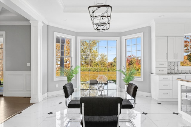 dining area featuring decorative columns, crown molding, and a chandelier