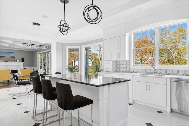 kitchen featuring dishwasher, decorative light fixtures, sink, white cabinetry, and tasteful backsplash