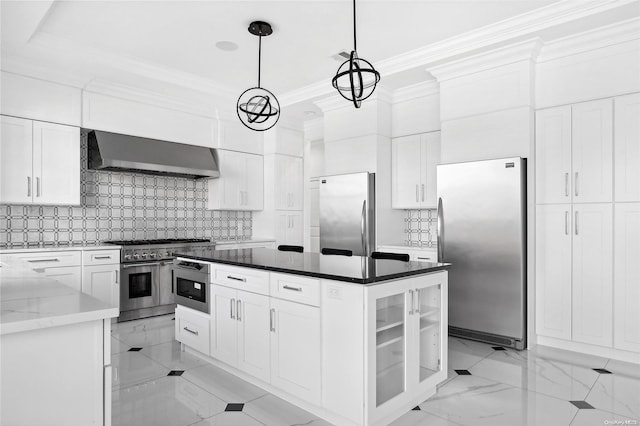 kitchen featuring appliances with stainless steel finishes, white cabinets, pendant lighting, dark stone counters, and wall chimney exhaust hood