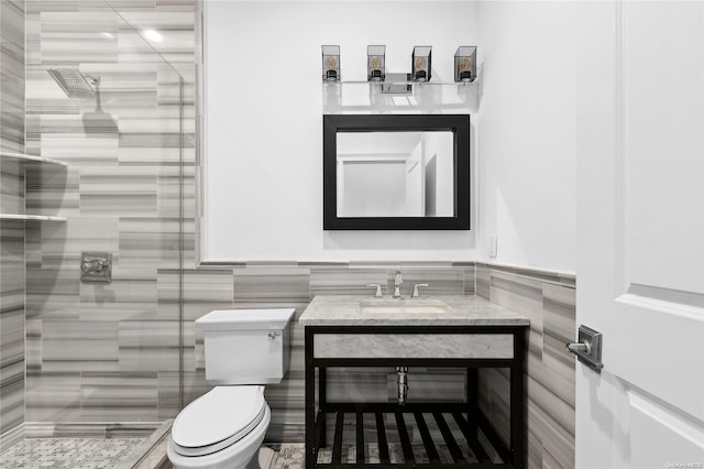 bathroom featuring tile walls, toilet, tiled shower, and vanity