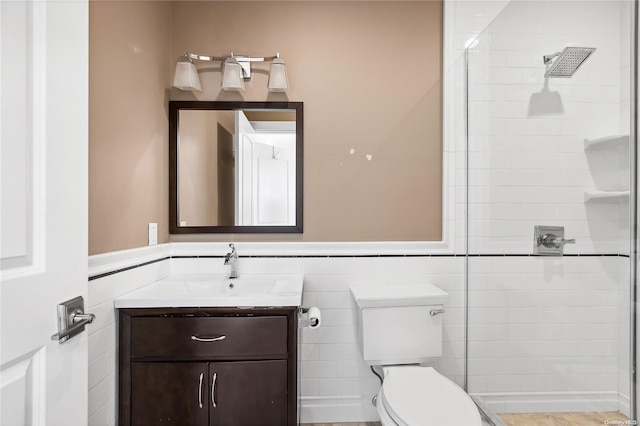 bathroom with vanity, toilet, a shower, and tile walls