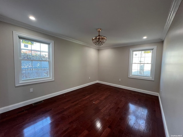 spare room featuring dark hardwood / wood-style floors, ornamental molding, and a notable chandelier