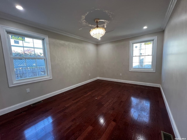 unfurnished room with dark hardwood / wood-style floors, plenty of natural light, crown molding, and an inviting chandelier