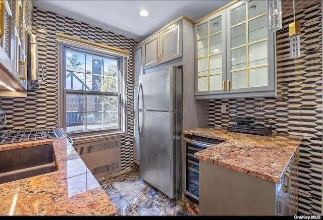 kitchen with backsplash, radiator, wine cooler, light stone counters, and stainless steel refrigerator